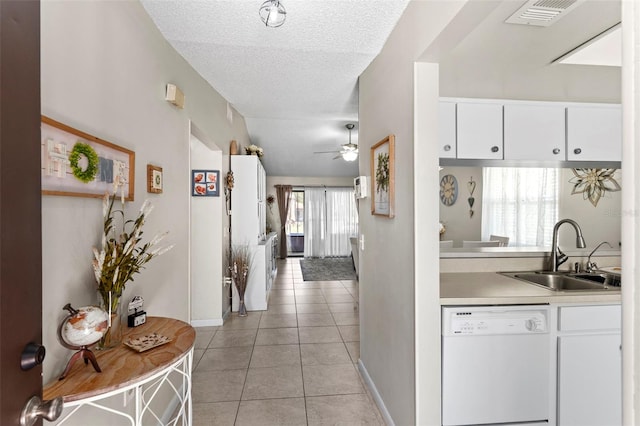 corridor featuring light tile patterned floors, a textured ceiling, visible vents, a sink, and baseboards