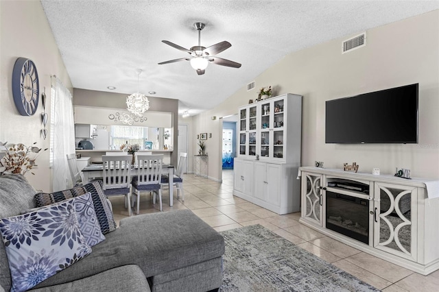 living room with visible vents, a textured ceiling, ceiling fan with notable chandelier, and lofted ceiling