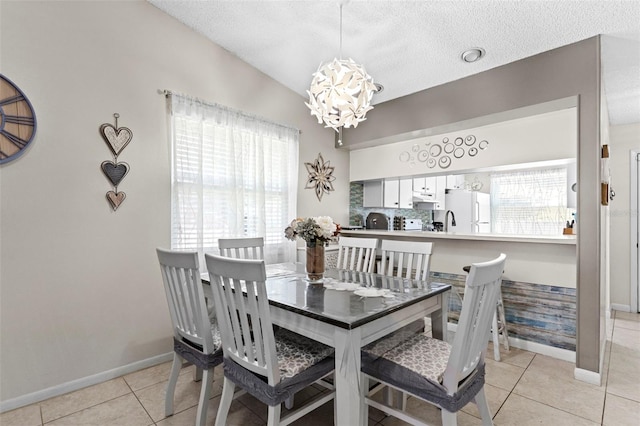 dining area with light tile patterned floors, baseboards, a chandelier, and a textured ceiling