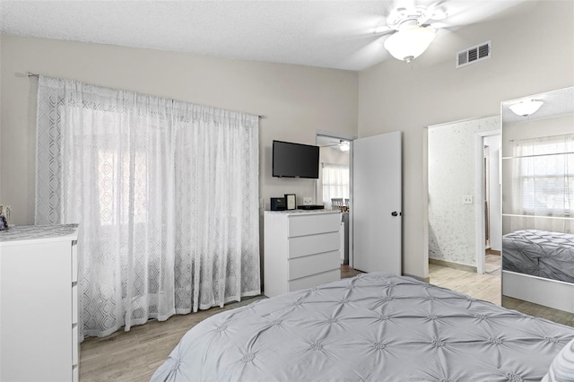 bedroom featuring visible vents, light wood-type flooring, and lofted ceiling