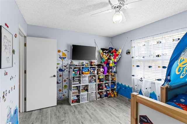 bedroom featuring ceiling fan, a textured ceiling, and wood finished floors