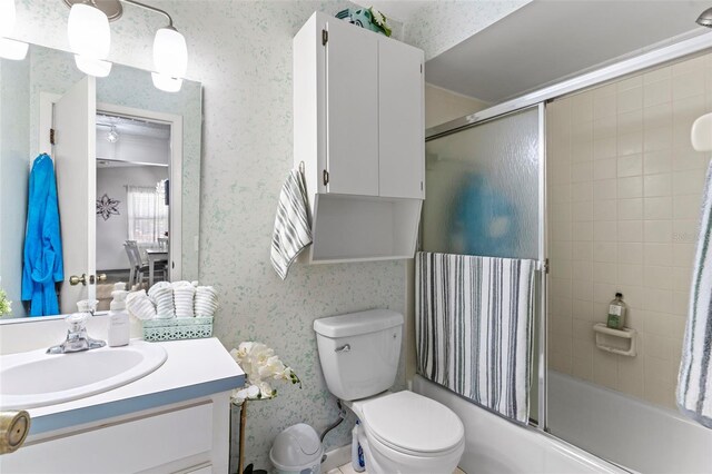 bathroom featuring toilet, vanity, wallpapered walls, and enclosed tub / shower combo