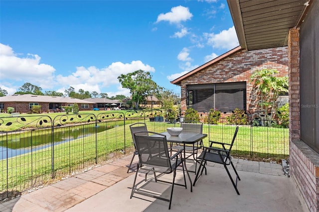 view of patio / terrace featuring fence, outdoor dining area, and a water view