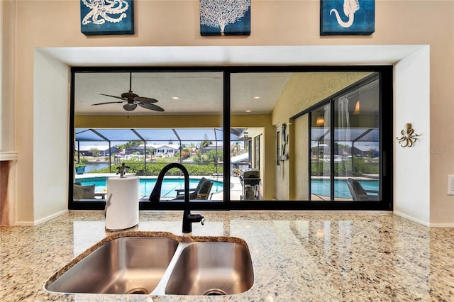 907 Golf Island Dr, Apollo Beach, FL 33572 - kitchen view of a sink, a sunroom, light stone countertops, ceiling fan, and a pool
