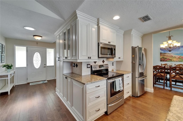 907 Golf Island Dr, Apollo Beach, FL 33572 - kitchen with stainless steel appliances, a chandelier, a textured ceiling, light wood-type flooring, and light stone countertops