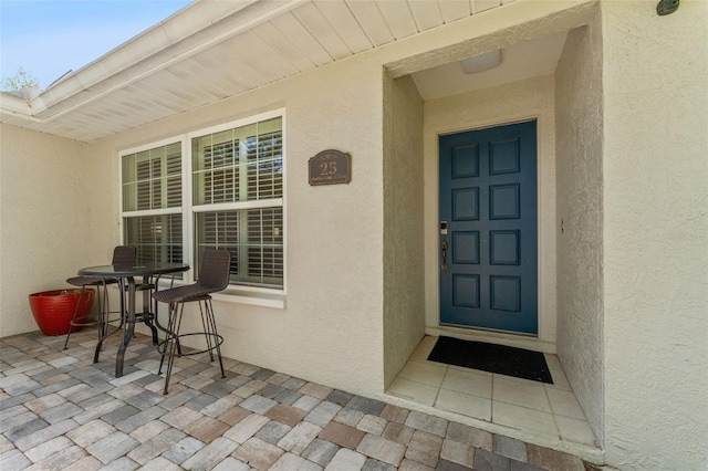 property entrance featuring stucco siding and a patio
