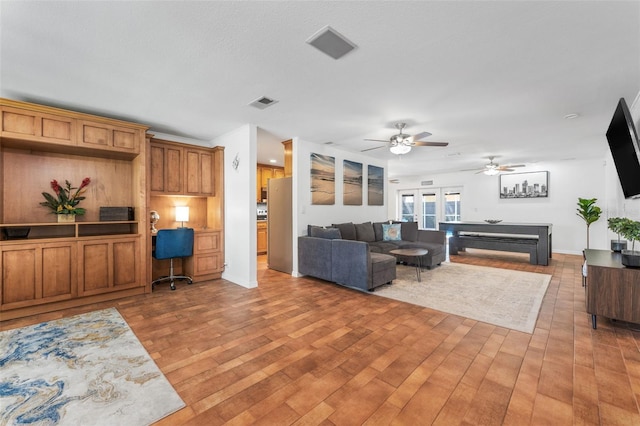 living area featuring a ceiling fan, light wood-style flooring, and baseboards