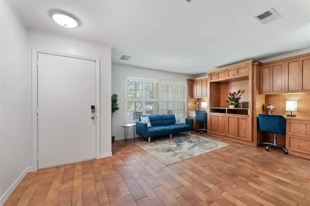 foyer featuring light wood finished floors, baseboards, built in study area, and ornamental molding