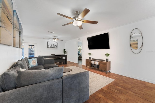 living area with a ceiling fan, wood finished floors, and baseboards