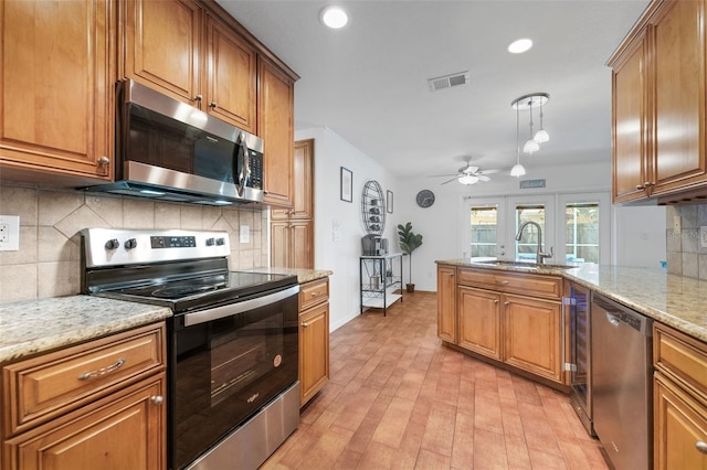 kitchen with appliances with stainless steel finishes, a sink, a ceiling fan, brown cabinets, and recessed lighting