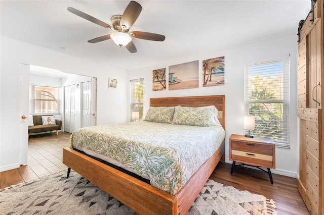 bedroom featuring wood finished floors, baseboards, a ceiling fan, and a closet