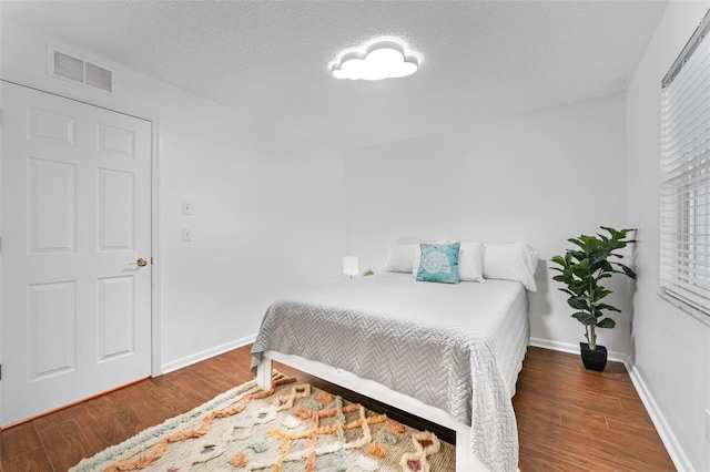 bedroom featuring wood finished floors, baseboards, and a textured ceiling