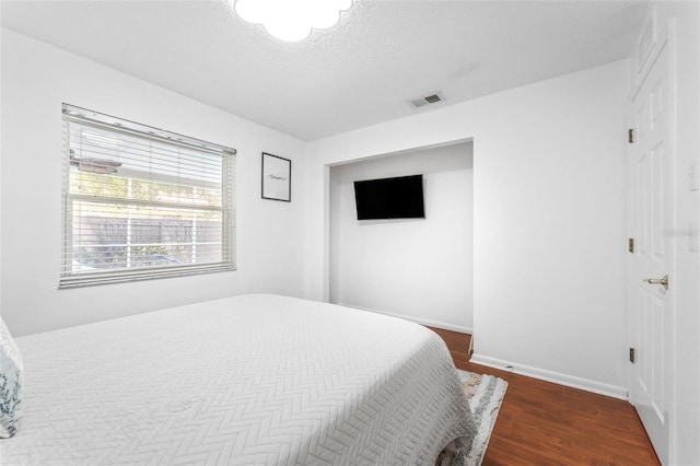 bedroom featuring wood finished floors, a textured ceiling, and baseboards