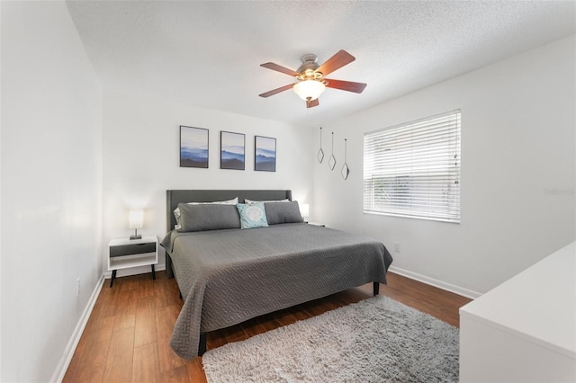 bedroom featuring baseboards, wood finished floors, and a ceiling fan
