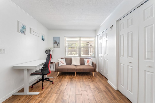office area with wood finished floors, a textured ceiling, and baseboards