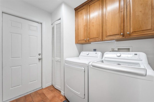 clothes washing area with washing machine and dryer, cabinet space, light wood-style floors, and baseboards
