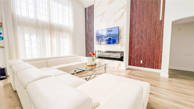 living room featuring baseboards, wood finished floors, arched walkways, and a healthy amount of sunlight