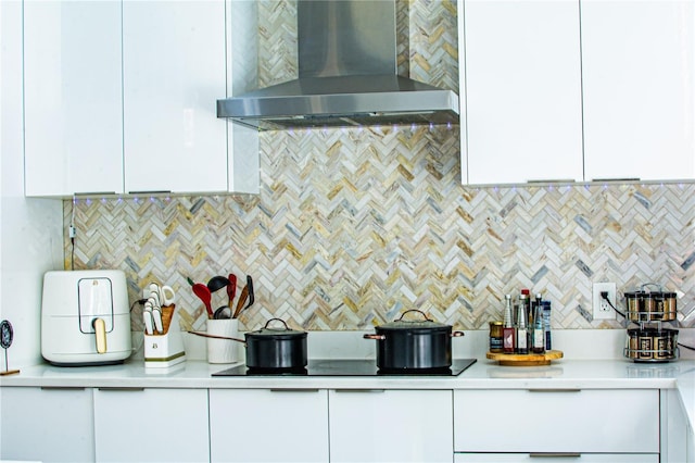kitchen featuring white cabinets, decorative backsplash, light countertops, and wall chimney range hood