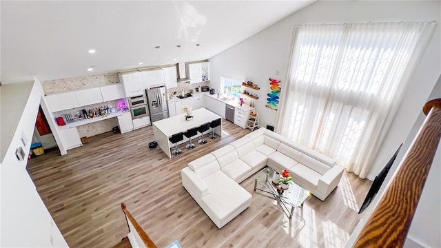 living area with vaulted ceiling, light wood finished floors, and recessed lighting