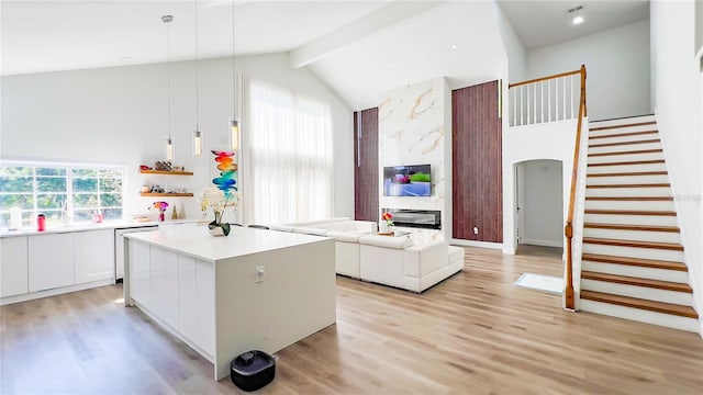 kitchen featuring high vaulted ceiling, a center island, light wood-style flooring, white cabinets, and dishwashing machine