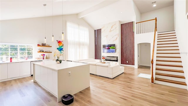 kitchen featuring white cabinets, light countertops, dishwashing machine, light wood-style floors, and a center island