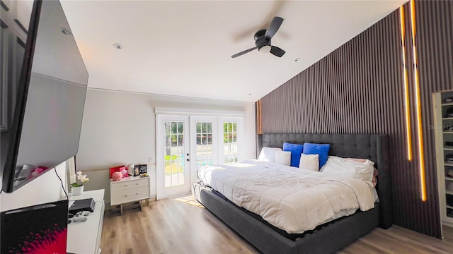 bedroom with an accent wall, wood finished floors, french doors, lofted ceiling, and access to exterior