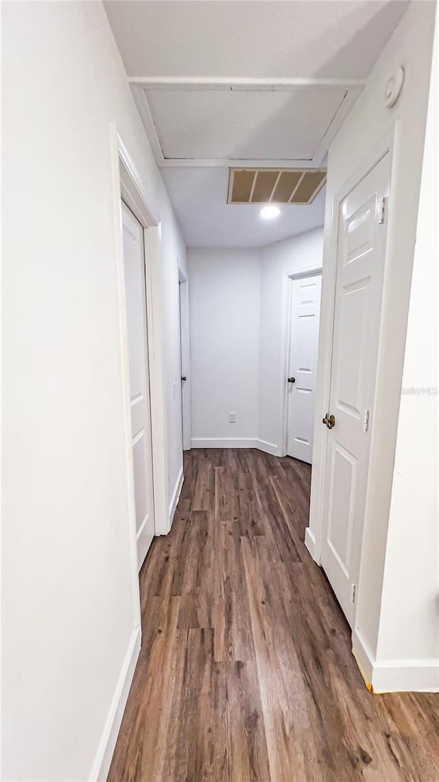 hall with visible vents, baseboards, and wood finished floors