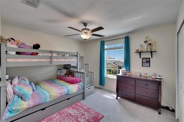 carpeted bedroom with visible vents, baseboards, a ceiling fan, and a textured ceiling