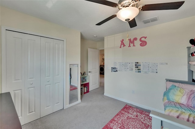 bedroom featuring visible vents, washer / clothes dryer, a closet, ceiling fan, and light carpet