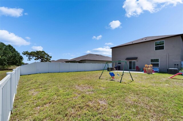 view of yard with a fenced backyard, cooling unit, and a playground