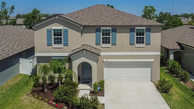 traditional-style home featuring stucco siding, roof with shingles, fence, an attached garage, and concrete driveway