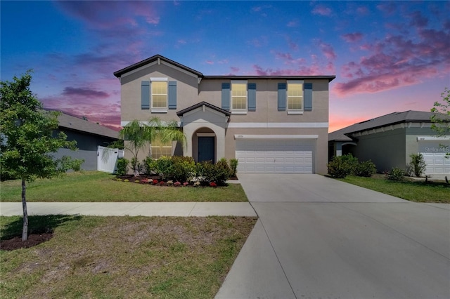 traditional home with an attached garage, driveway, stucco siding, and a front yard