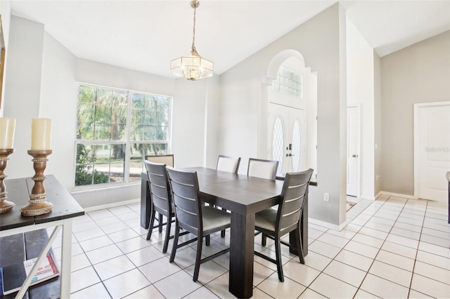 dining room featuring baseboards, a notable chandelier, vaulted ceiling, and light tile patterned floors