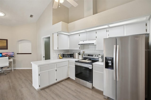 kitchen with high vaulted ceiling, tasteful backsplash, appliances with stainless steel finishes, a peninsula, and under cabinet range hood