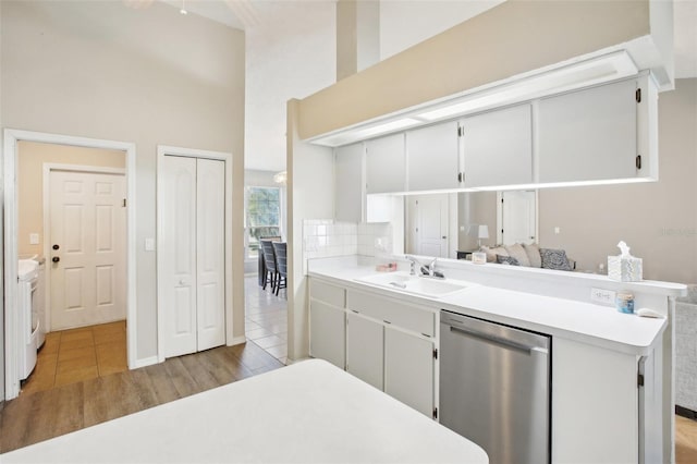 kitchen featuring light wood finished floors, stainless steel dishwasher, light countertops, and a sink
