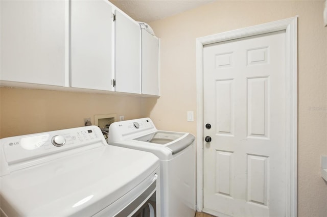 clothes washing area with separate washer and dryer and cabinet space