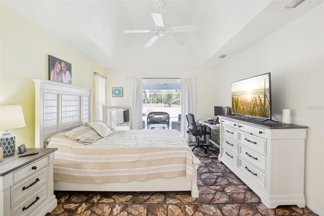 bedroom featuring access to outside, vaulted ceiling, stone finish flooring, and a ceiling fan