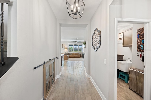 4108 Mellon Dr, Odessa, FL 33556 - hallway featuring baseboards, a barn door, an inviting chandelier, a sink, and light wood-style floors