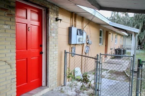 entrance to property with stucco siding, a gate, fence, and brick siding