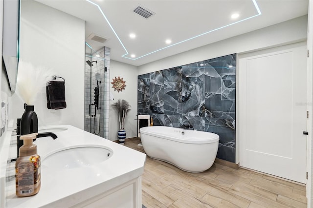 506 Spring Tree Ct, Tarpon Springs, FL 34689 - bathroom with tile walls, a shower stall, double vanity, a freestanding tub, and wood finished floors