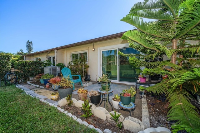 rear view of house with a patio, stucco siding, and central AC