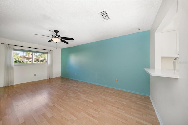 spare room featuring ceiling fan, light wood-style flooring, baseboards, and visible vents