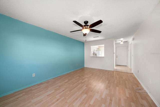 spare room with ceiling fan, light wood-style flooring, and baseboards