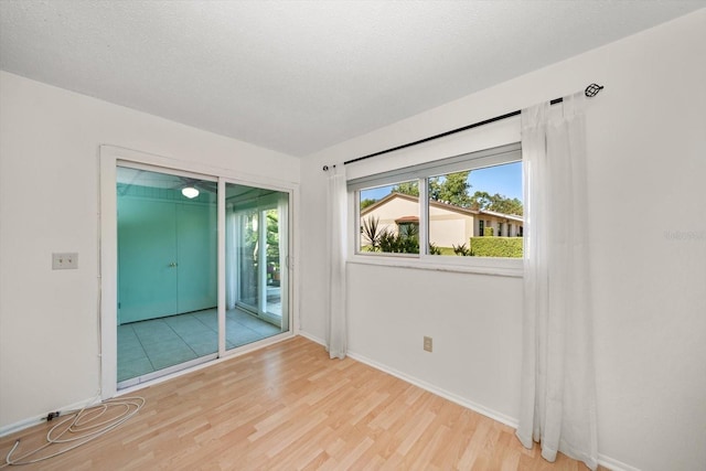 spare room with baseboards, a healthy amount of sunlight, and wood finished floors