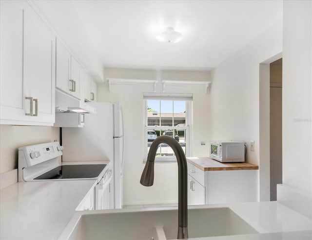 kitchen with a sink, white cabinets, white appliances, under cabinet range hood, and butcher block counters