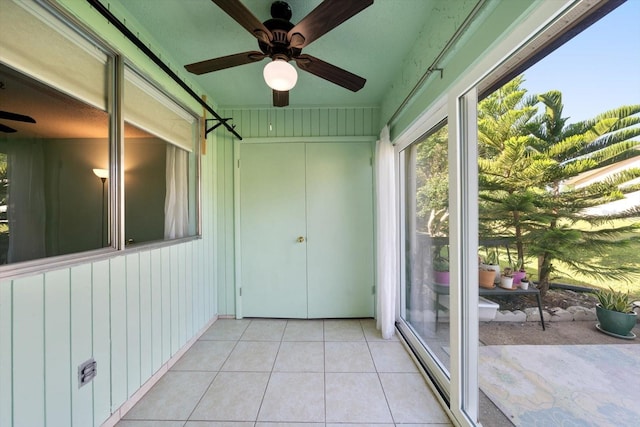 unfurnished sunroom featuring a ceiling fan and tile patterned flooring