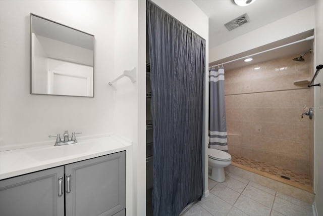full bathroom with toilet, tiled shower, tile patterned floors, visible vents, and vanity