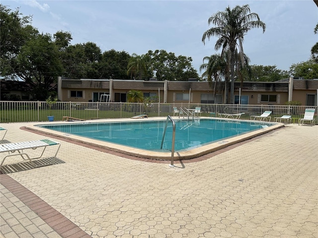 community pool with fence and a patio area