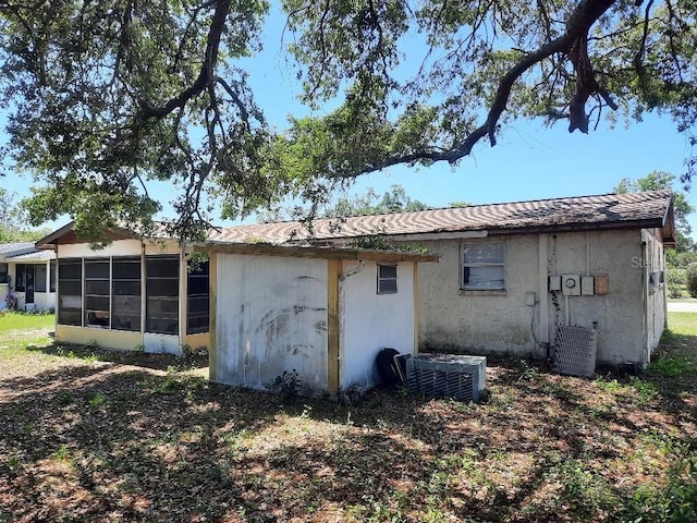 9355 Pinero St, Spring Hill, FL 34608 - rear view of house featuring a sunroom, stucco siding, and central AC
