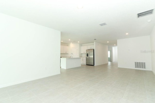 unfurnished living room featuring baseboards, a sink, visible vents, and recessed lighting